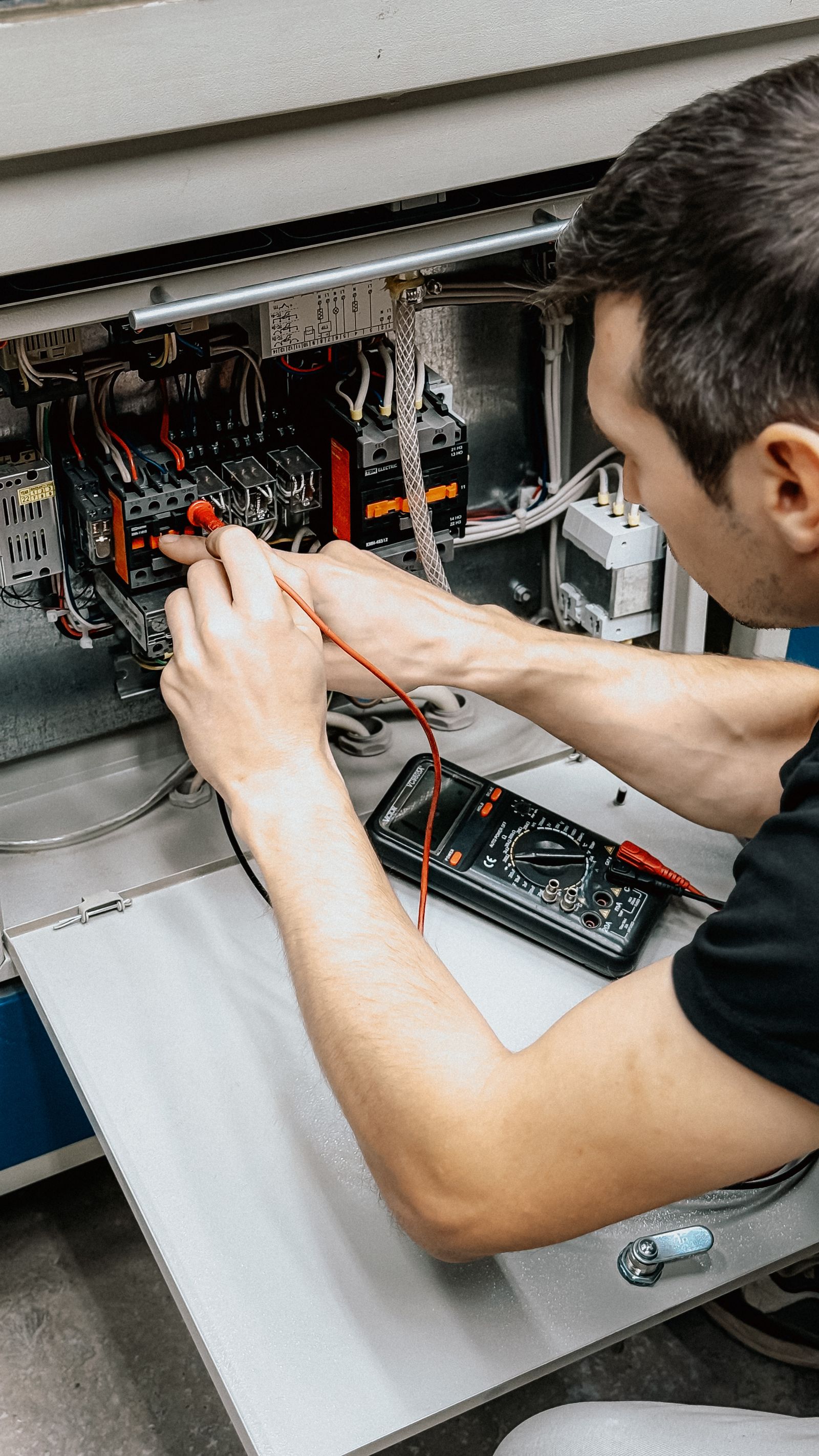 An electrician inspecting wiring inside a residential electrical panel