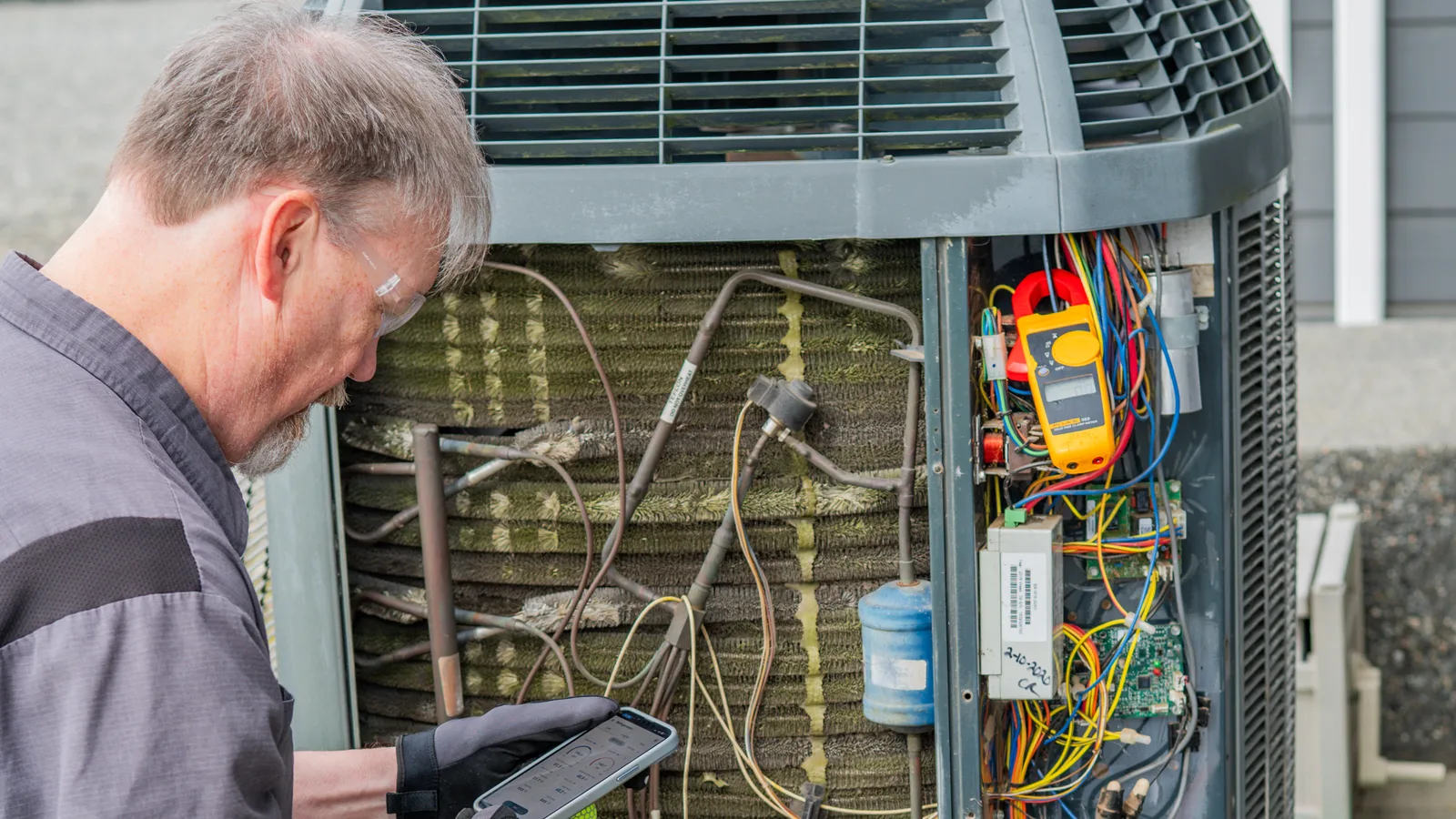 Andgar technician diagnosing an outdoor heat pump